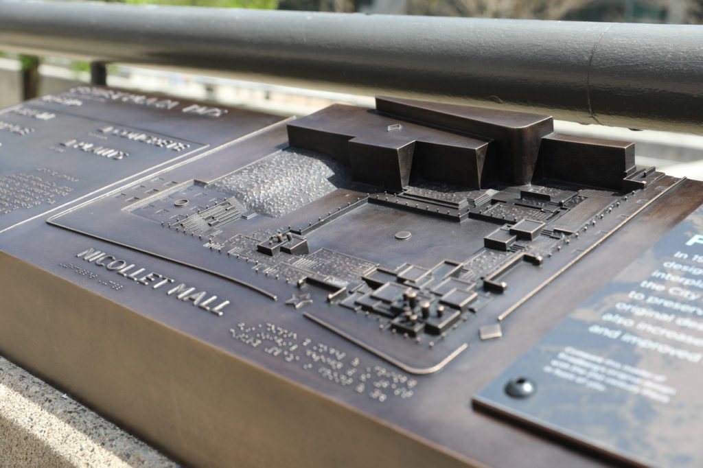 A bronze tactile element with a scale model of a city park’s architecture.