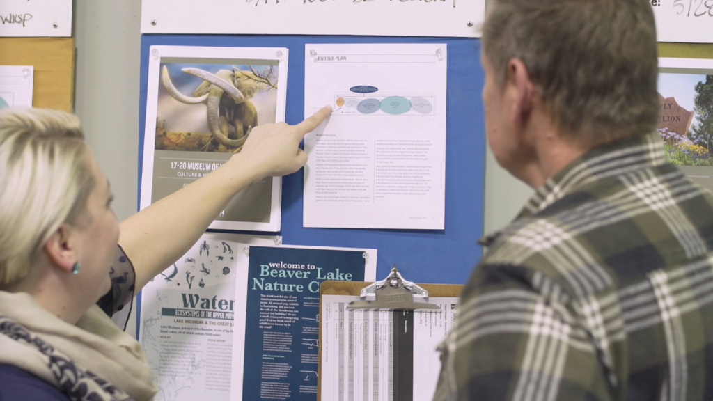 This photo shows team members, such as a project manager, review exhibition plans for a Taylor Studios project.